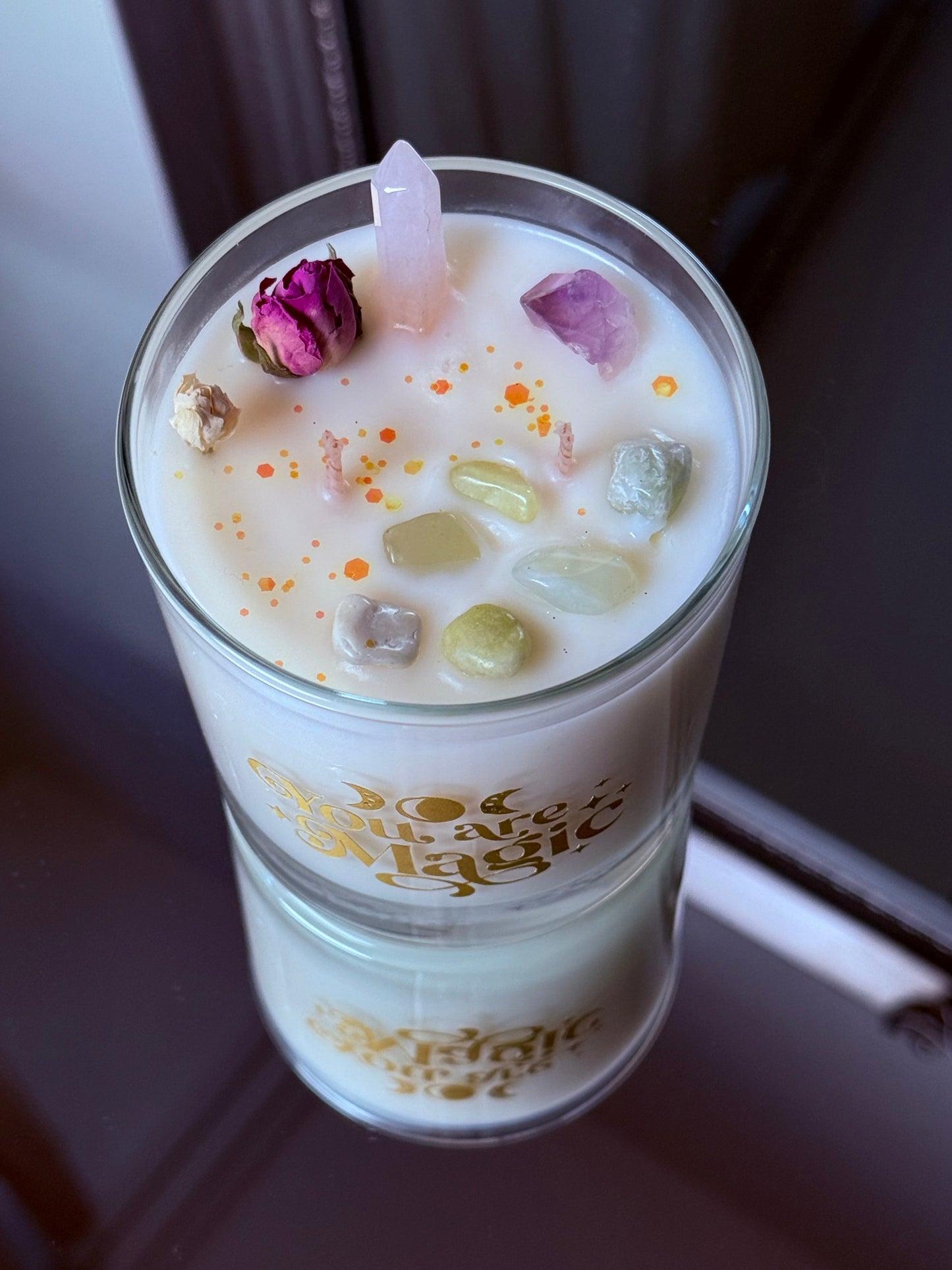 Nahaufnahme der Kerzenoberfläche mit echter Rosenquarz-Spitze, violettem Amethyst, grüner Jade und getrockneten Rosenknospen im Wachs.