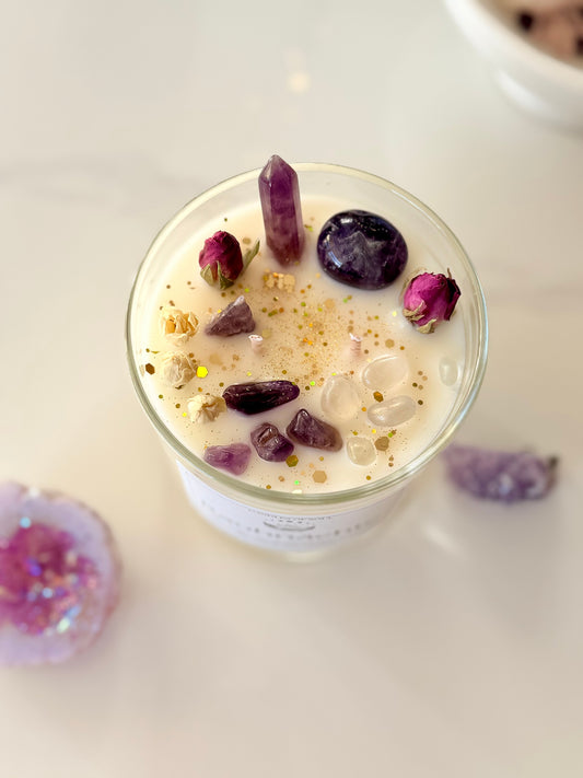 "Draufsicht handgemachte Sojawachskerze dekoriert mit lila Amethyst Heilsteinen und getrockneten Rosenknospen."