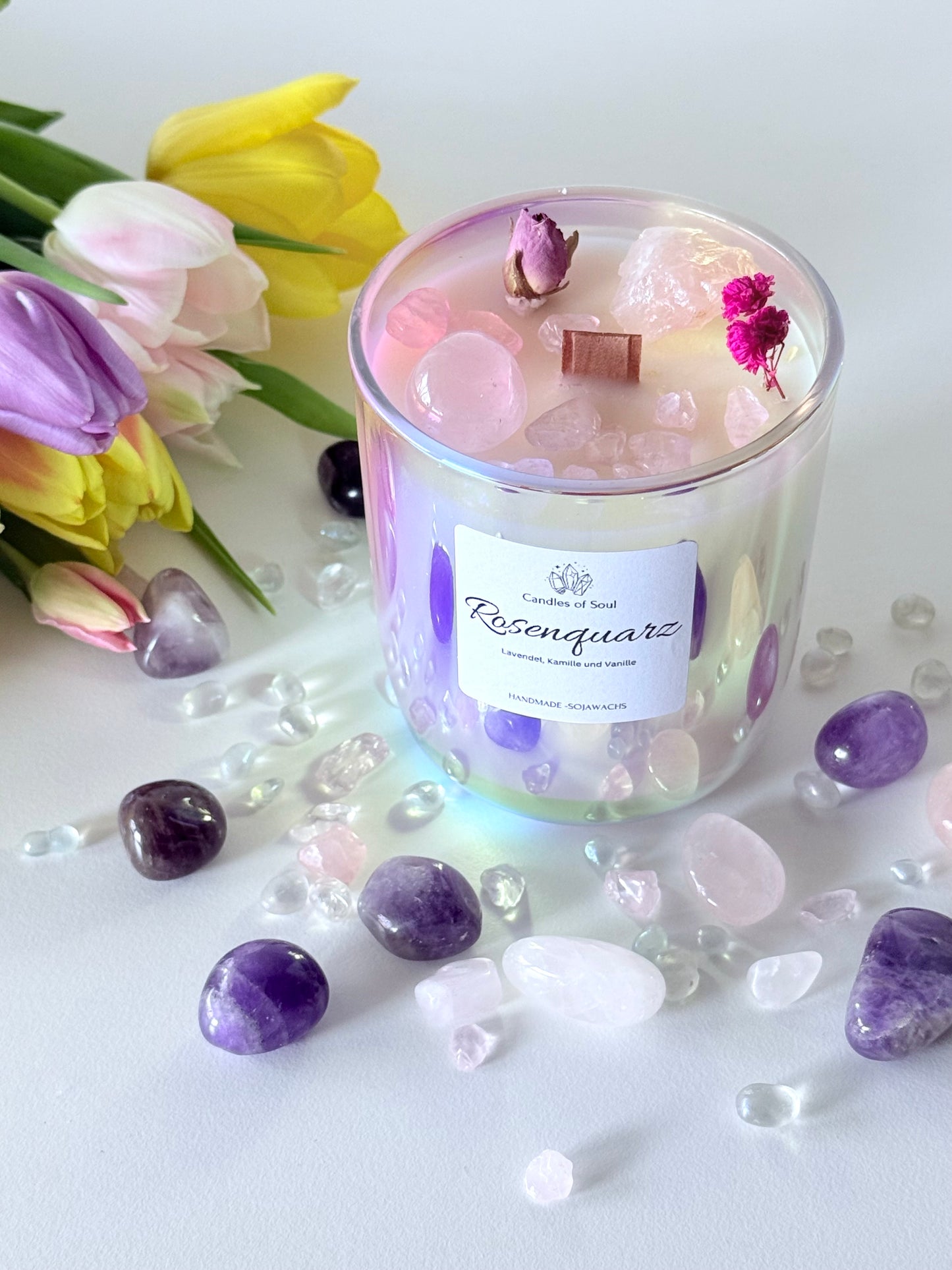 Handgemachte Rosenquarz Duftkerze mit Edelsteinen, umgeben von Amethysten und Bergkristallen.