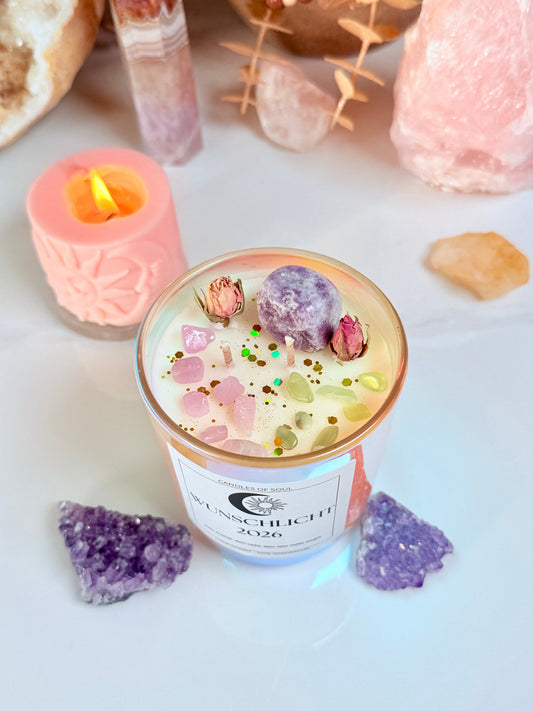 Detailfoto der Kristallkerze mit Edelsteinen (Rosenquarz, Jade, Lepidolith) und Blüten auf Marmortisch.