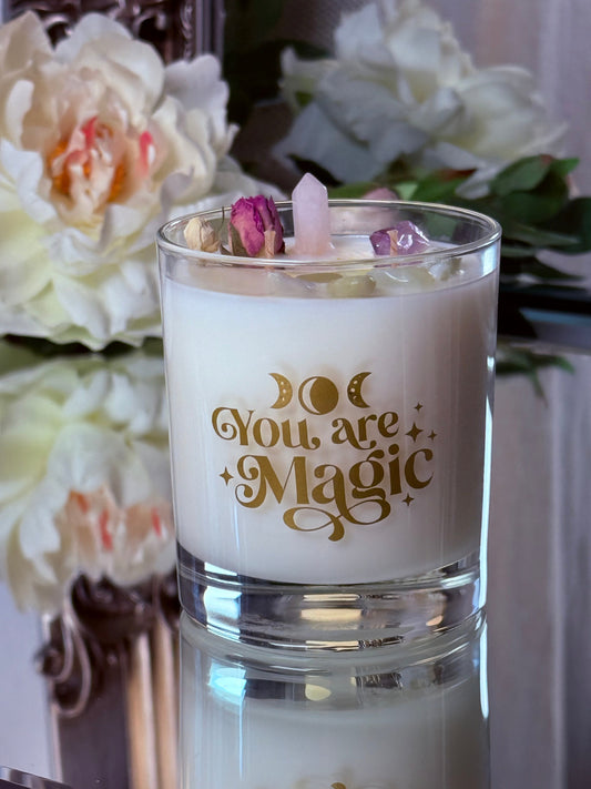 Vorderseite der Sojawachskerze im Glas mit goldenem "You are Magic" Schriftzug und Mondphasen, dekoriert mit einer Rosenquarz-Spitze.