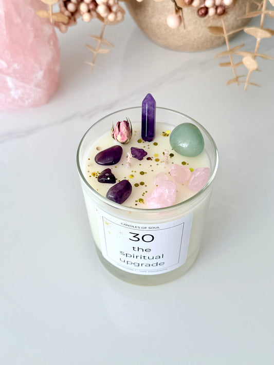 Spirituelle Duftkerze mit Edelsteinen und getrockneter Rose auf weißem Hintergrund.