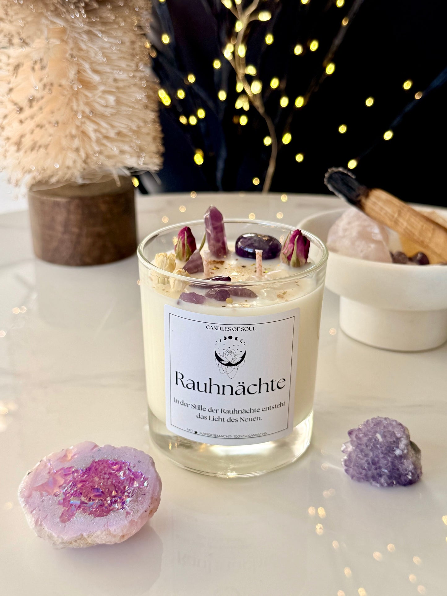 Spirituelle Deko für Rauhnächte Rituale: Brennende Kerze mit Kristallen und Bokeh Lichtern im Hintergrund.