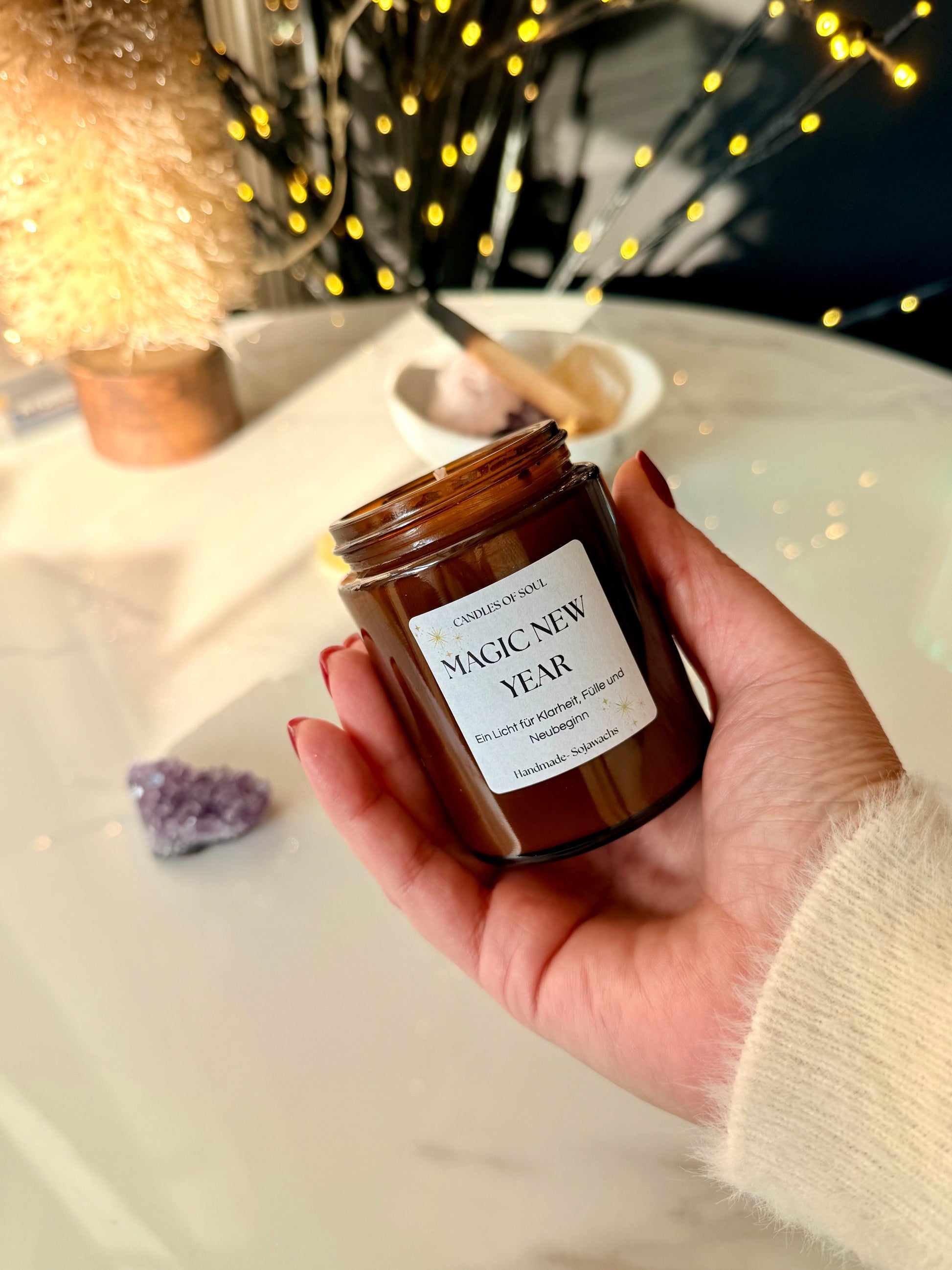 Hand hält Neujahrskerze im Braunglas mit Label Magic New Year, ideal als persönliches Silvester Geschenk.