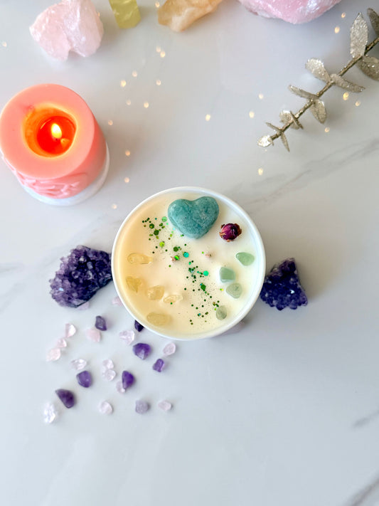 Draufsicht auf handgemachte Kristallkerze, Amazonit Herzstein, gelbe Citrin Edelsteine und getrocknete Rosenknospe auf cremeweißem Sojawachs, spirituelle Deko