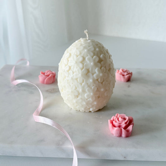 Handgefertigte Osterei-Kerze in Cremeweiß mit filigranem Blumenmuster, perfekt für Osterdeko und Geschenke.