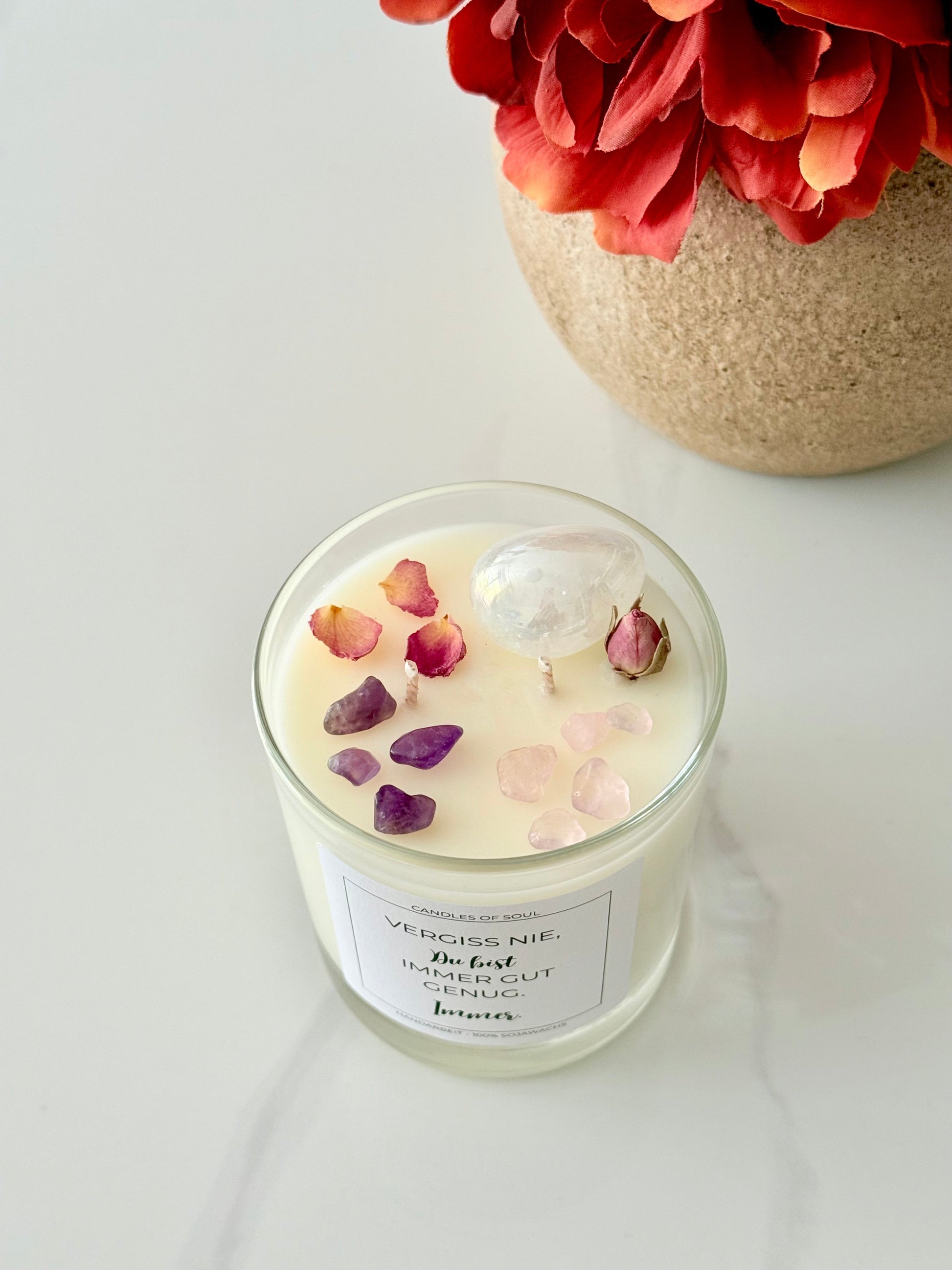 Vegane Duftkerze mit Kristallen und Affirmation auf weißem Untergrund