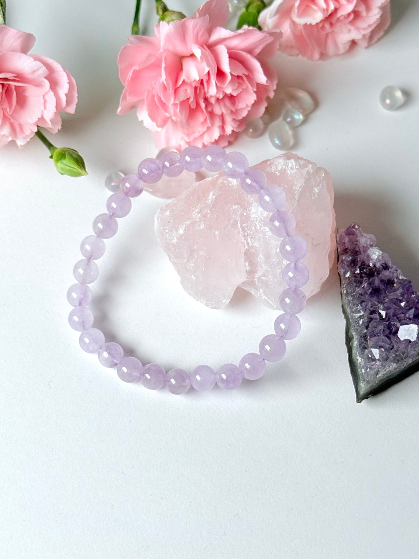 Handgemachtes Lavendel-Amethyst Armband aus 6mm Kugeln auf weißem Hintergrund mit Rosen und Kristallen