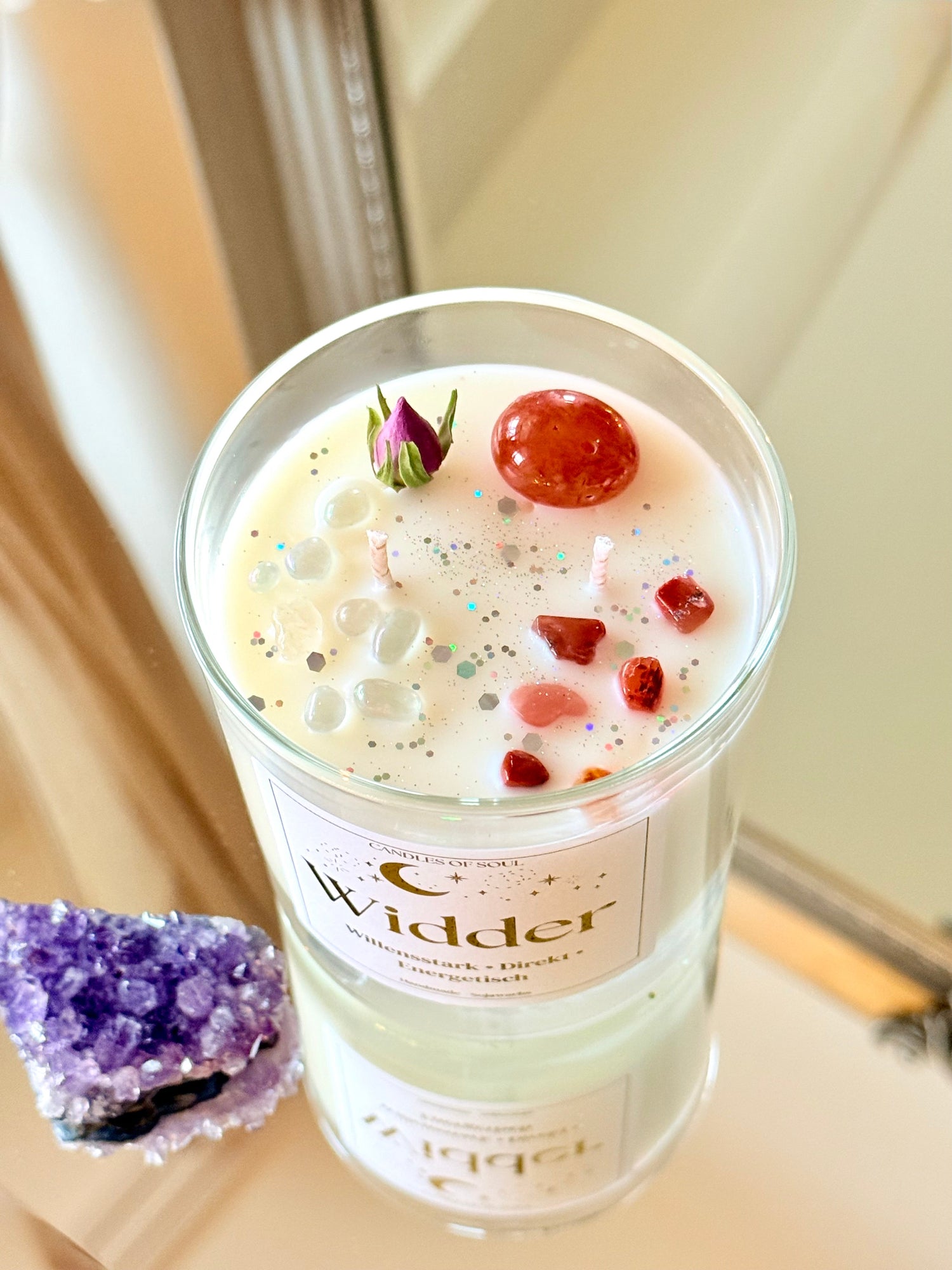 Spirituelle Dekoration mit einer Widder-Edelsteinkerze auf einer spiegelnden Oberfläche.