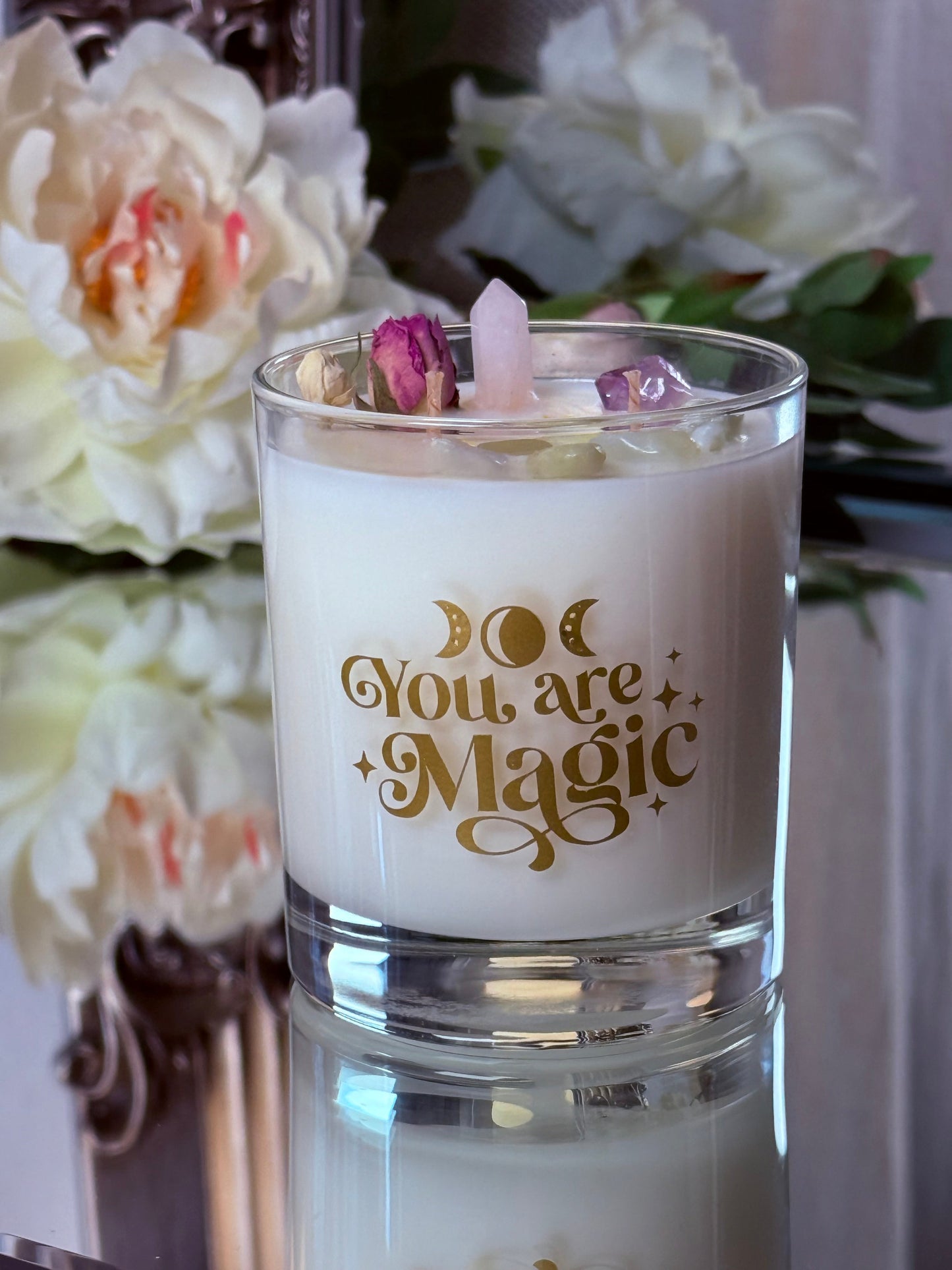 Vorderseite der Sojawachskerze im Glas mit goldenem "You are Magic" Schriftzug und Mondphasen, dekoriert mit einer Rosenquarz-Spitze.