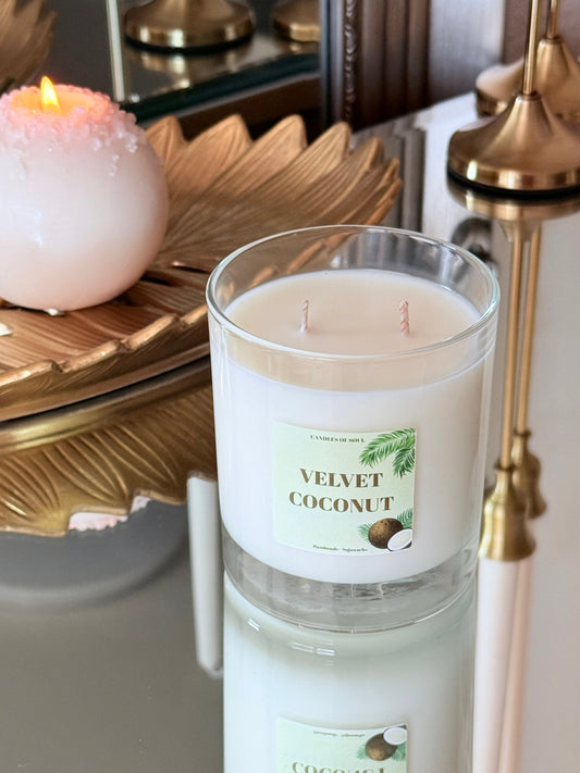 Weiße handgefertigte Kokoskerze spiegelt sich auf einer eleganten Glasoberfläche.