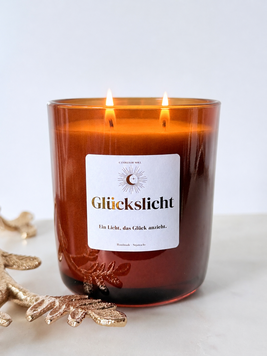 Glückslicht Duftkerze aus Sojawachs im braunen Glas mit weißem Etikett und dem Motto Ein Licht, das Glück anzieht