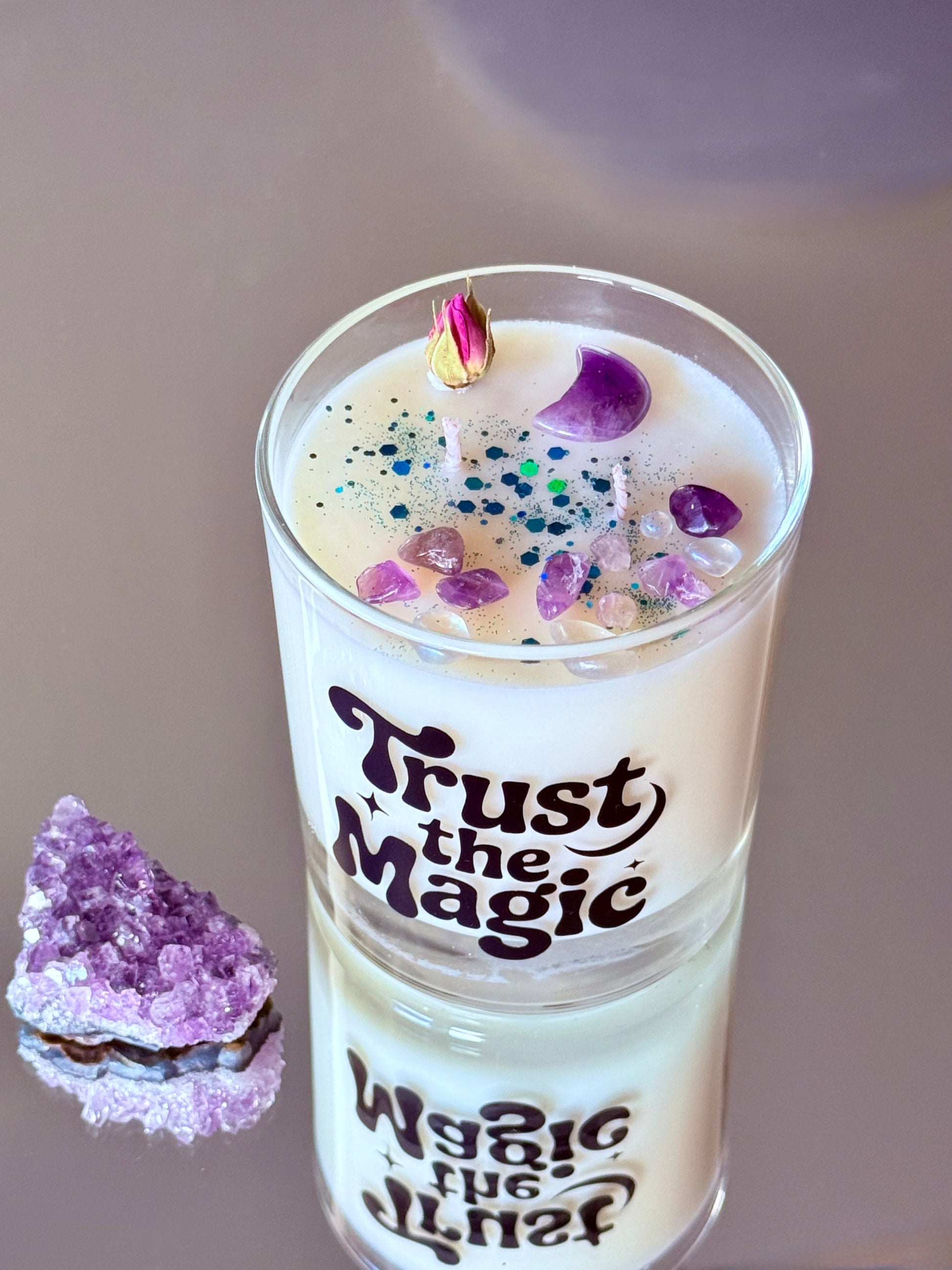 Detailansicht der Kerzenoberfläche, zeigt einen geschliffenen Amethyst in Mondform, Amethyst-Splitter, eine getrocknete Rosenknospe und funkelnden Eco-Glitzer im Wachs.