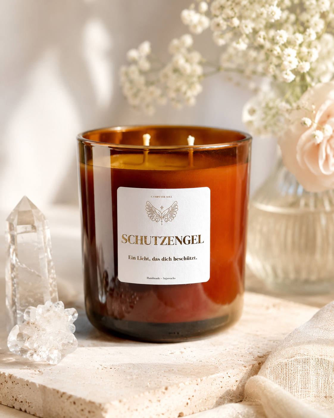Handgemachte Sojawachs-Kerze Schutzengel mit zwei Flammen, eleganter Gold-Label-Optik und stilvoller beige-goldener Dekoration.
