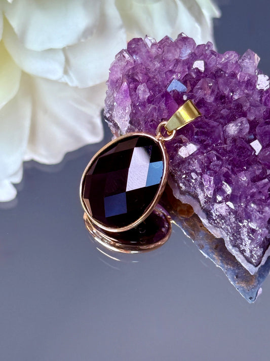 Ovaler Anhänger aus schwarzem Obsidian Edelstein in goldener Fassung, facettiert.