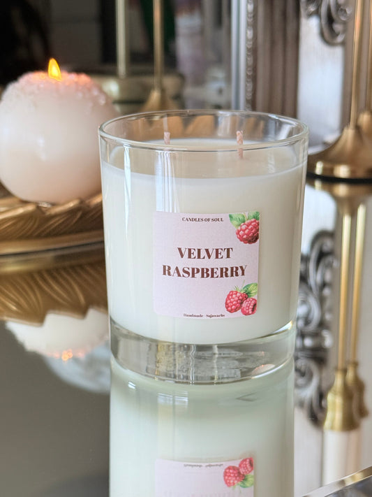 Brennglas-Kerze mit Himbeerduft auf einer spiegelnden Oberfläche in eleganter Atmosphäre.