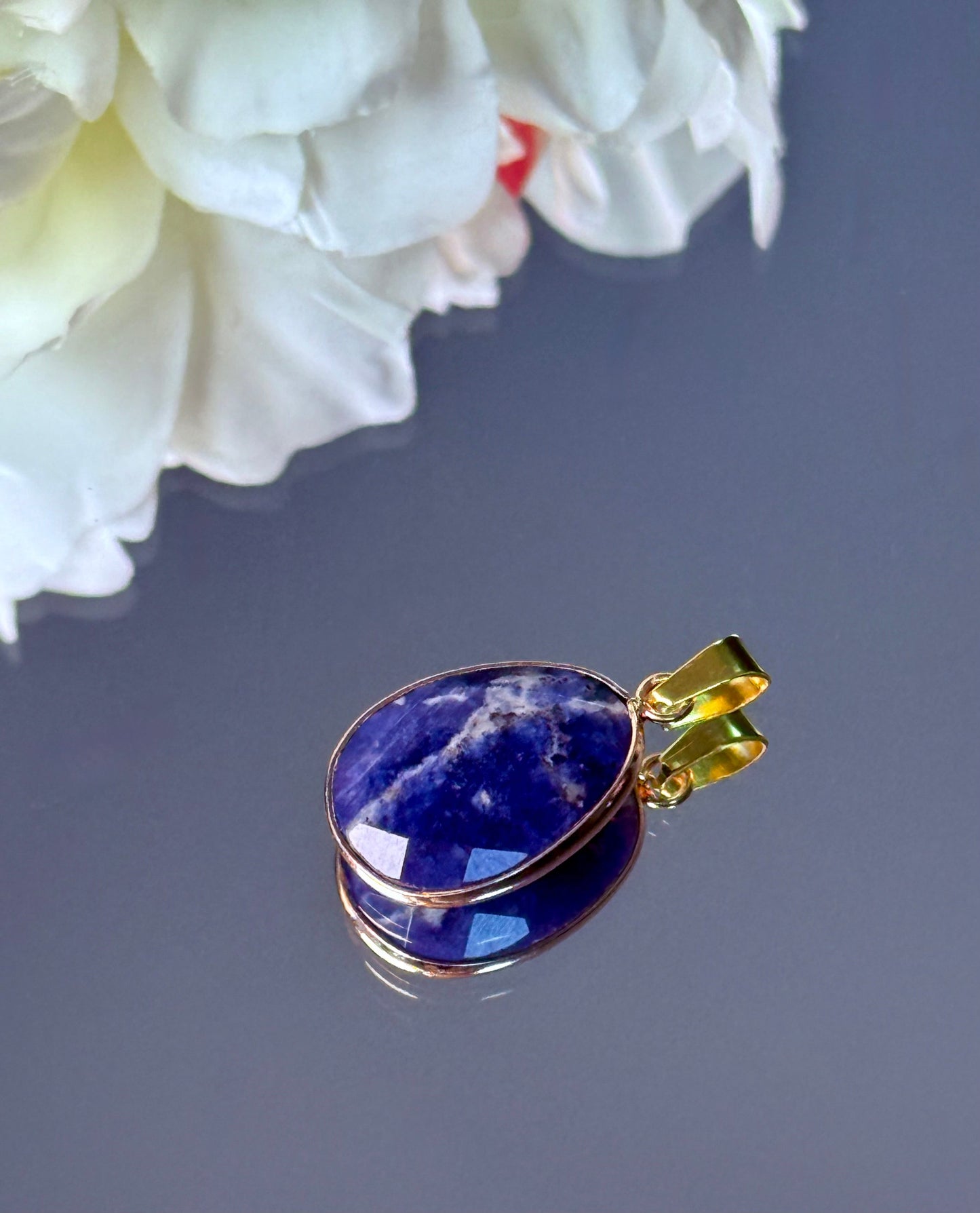 Blauer Sodalith Edelstein Anhänger dekorativ an einer Amethyst-Druse lehnend