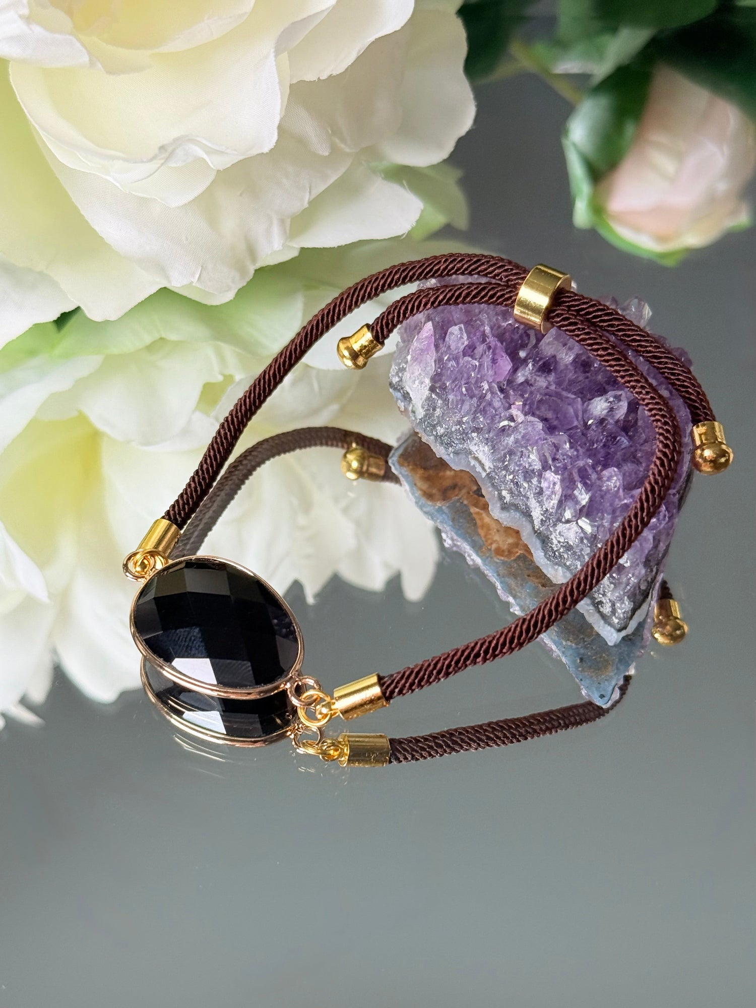 Elegantes Goldarmband mit tiefschwarzem Obsidian-Edelstein, liegend auf neutralem Hintergrund.