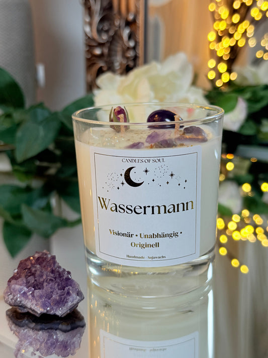 Wassermann Kerze neben einem großen Amethyst-Rohstein auf einer spiegelnden Fläche.