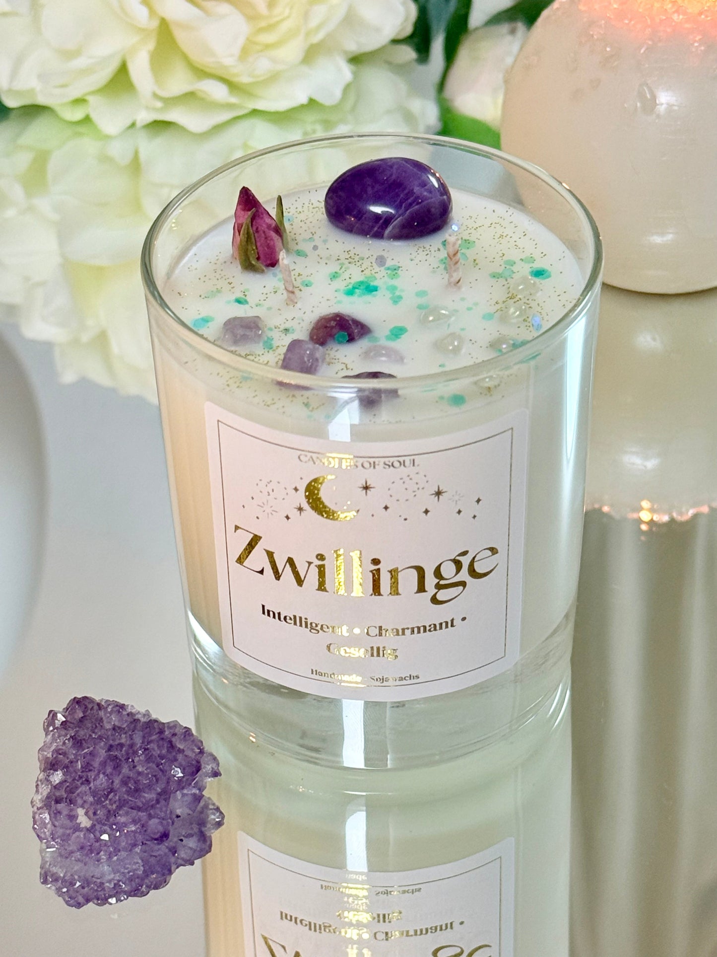 Nahaufnahme der Zwillinge-Kerze mit Amethyst-Steinen und türkisfarbenem Glitzer im weißen Wachs.